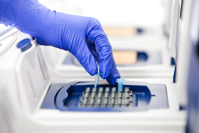 close up of gloved scientist putting tubes in a real-time cycler